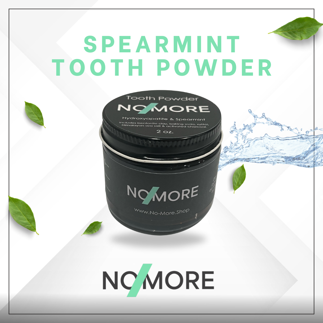 A container of NoMore Spearmint Mineral Tooth Powder with Charcoal, surrounded by graphic elements suggesting the product's natural ingredients and benefits, such as a splash of water and leaves.